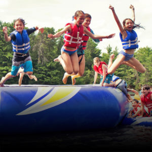 campers jumping off water trampoline