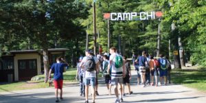 people with backpacks walking under the Camp Chi sign