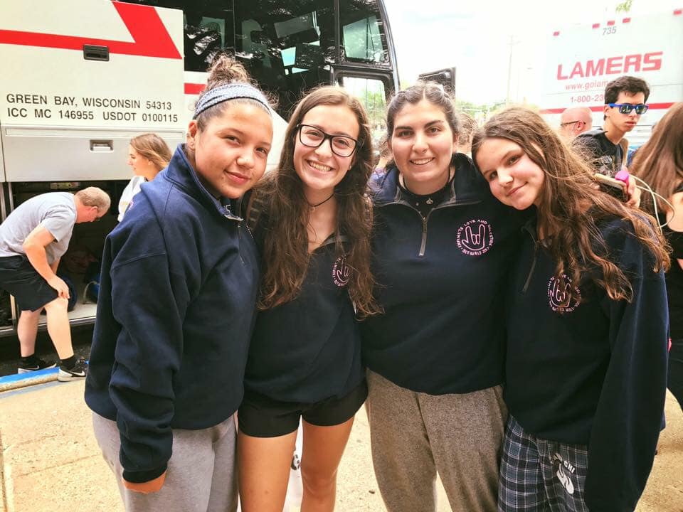 girls smiling outside of the Camp Chi buses