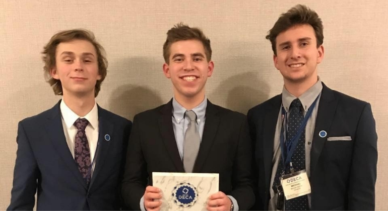 high school boys in suits holding DECA award