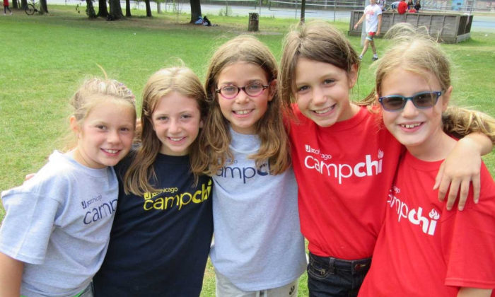 group of girls all wearing Camp Chi shirts smile at the camera with their arms around each other