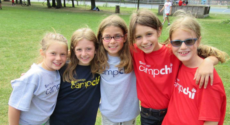 group of girls all wearing Camp Chi shirts smile at the camera with their arms around each other