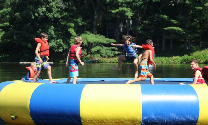 campers playing on the water trampoline out on the lake