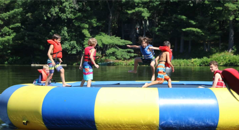 campers playing on the water trampoline out on the lake