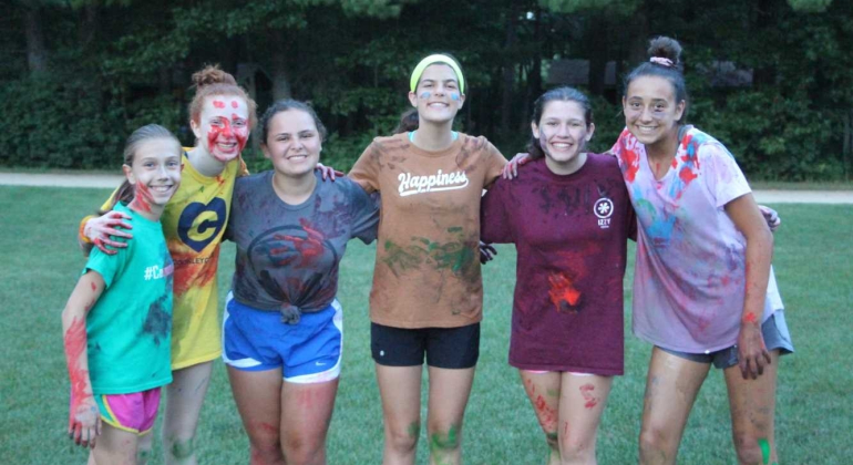 girls covered in paint smiling at the camera