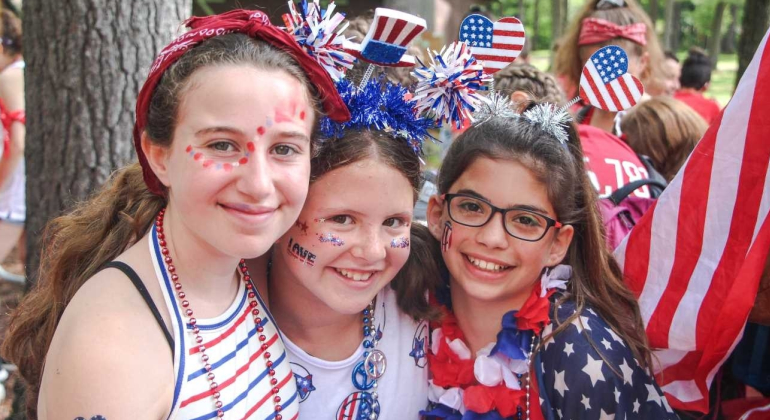girl campers with red white and blue face paint/outfits smiling for camera