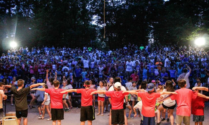 campers in red shirts performing something for the rest of camp at night