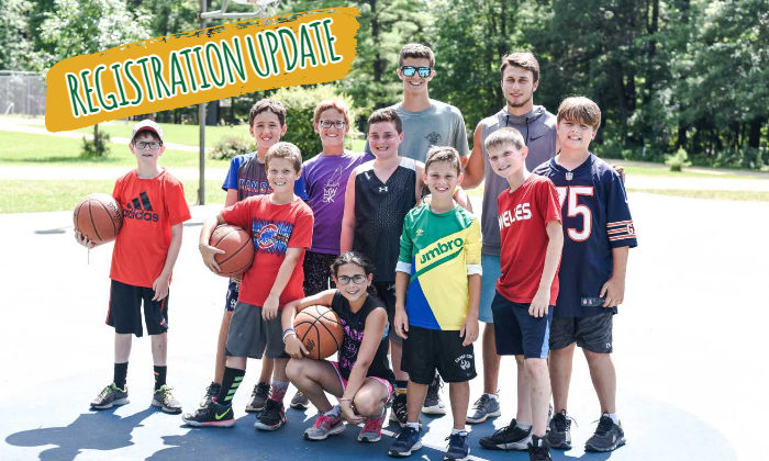 group of campers and two counselors posing with basketballs on the basketball court