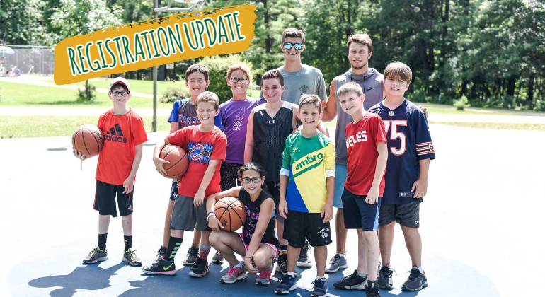 group of campers and two counselors posing with basketballs on the basketball court
