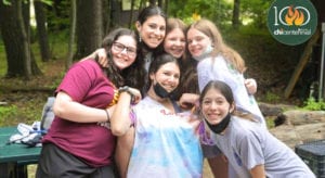 girls with masks sitting together at a picnic table and smiling for the camera