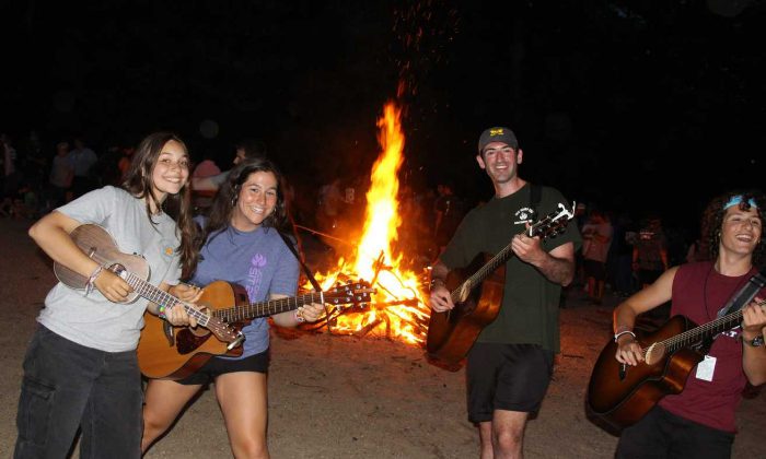 campers jamming out with their guitars by the bonfire