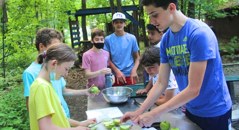 a counselor cutting up apples for his campers at Outdoor Cooking