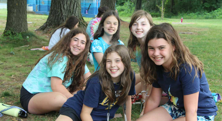 campers sitting together outside and smiling for the camera