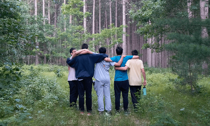 campers standing in the woods with their arms around each other