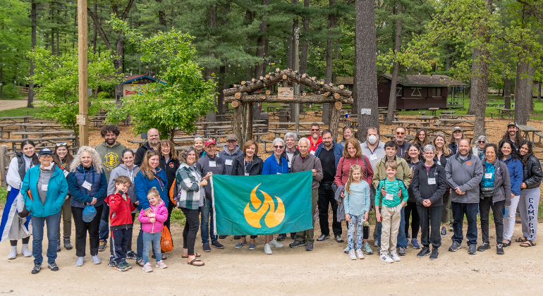 group of people from numerous different generations holding a Camp Chi flag