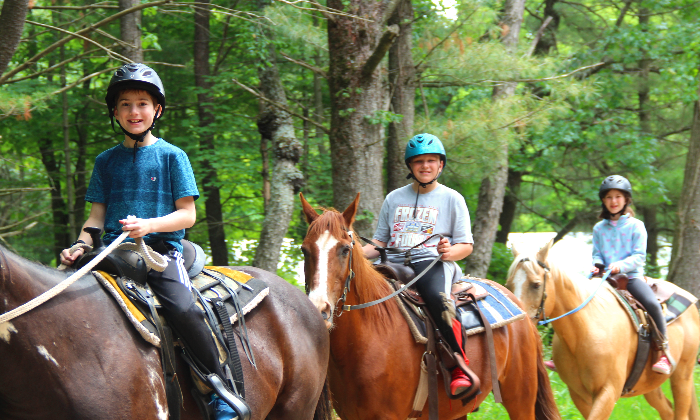 campers riding horses on a trail ride