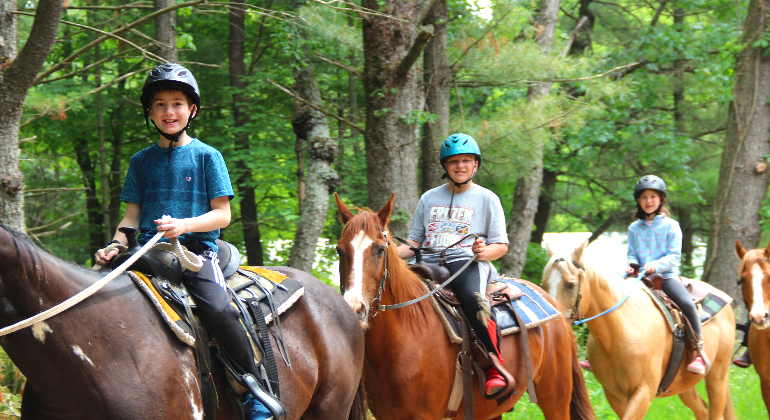 campers riding horses on a trail ride