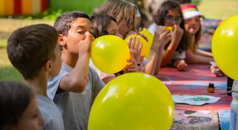 group of kids blowing up yellow balloons