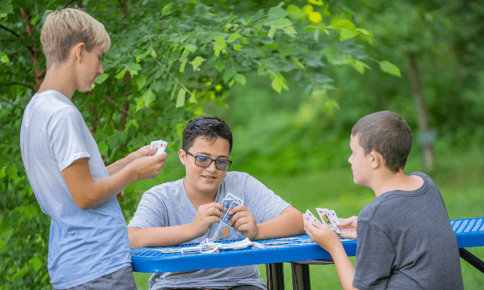 campers playing cards at a picnic table