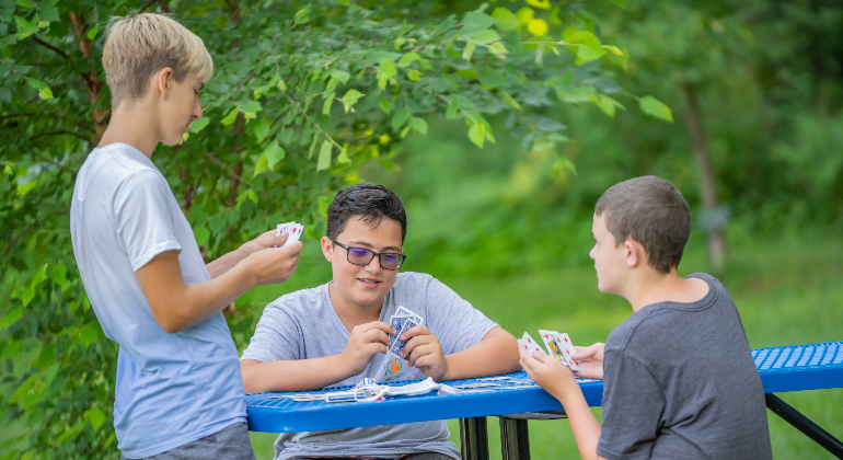 campers playing cards at a picnic table